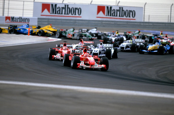 2004 FIA Formula 1 (F1) World Championship
Bahrain Grand Prix, Sakhir, Bahrain. 2nd - 4th April.
Michael Schumacher, Ferrari F2004 and Rubens Barrichello, Ferrari F2004 lead the field early on lap 1. Action. 
World Copyright: Michael Cooper/LAT Photographic 
ref: 35mm Transparency Image A14